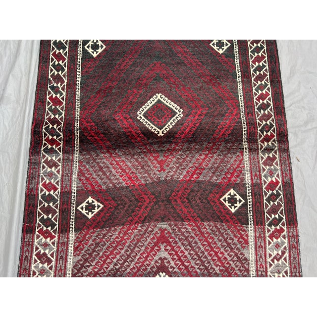 This vintage Afghan Baluchi hand-knotted wool runner features a captivating diamond lattice design in rich hues of...