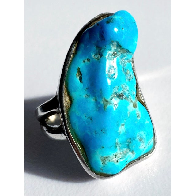 This striking vintage statement ring showcases a magnificent freeform slice of genuine Arizona blue turquoise, celebrated...