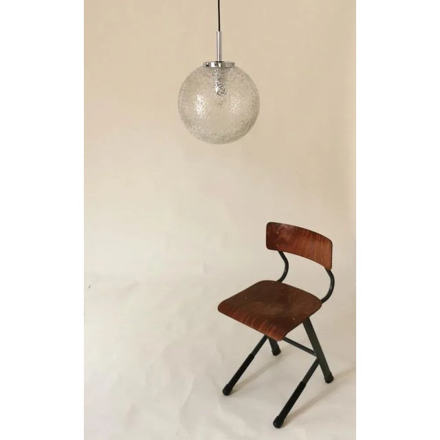 This ceiling lamp consists of corrugated glass and chrome elements, dates from the 1960s and was designed by the...