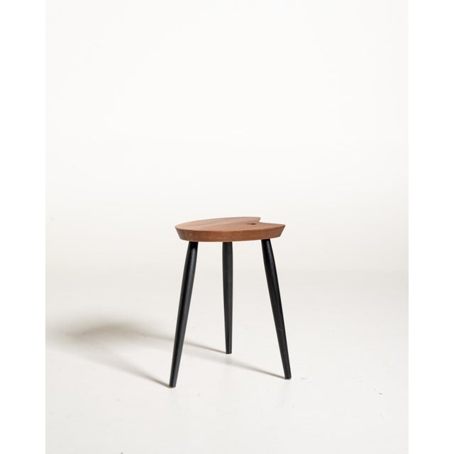 Scandinavian teak stool from the 1950s, featuring a distinctive palette-shaped seat with a circular hole and three...