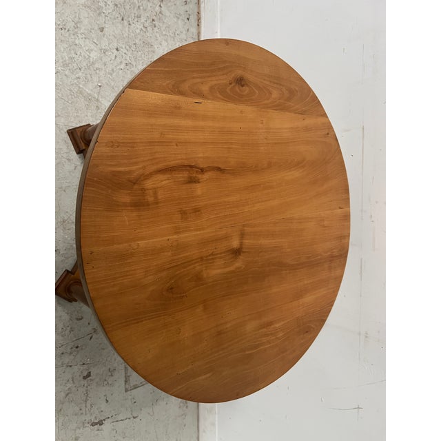 Round Empire-style cherrywood side table Three columned legs joined by an X-shaped stretcher Cherrywood top Good condition...