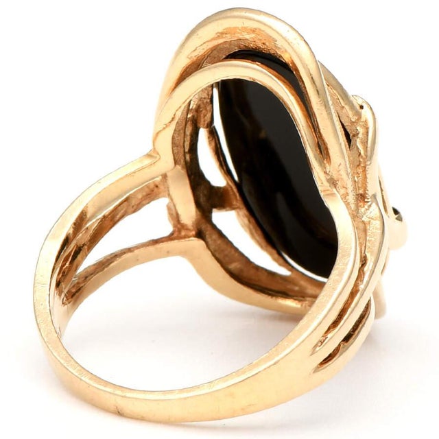 This bold and captivating 14K yellow gold ring features a smooth oval onyx stone set in a beautifully textured band. It's...