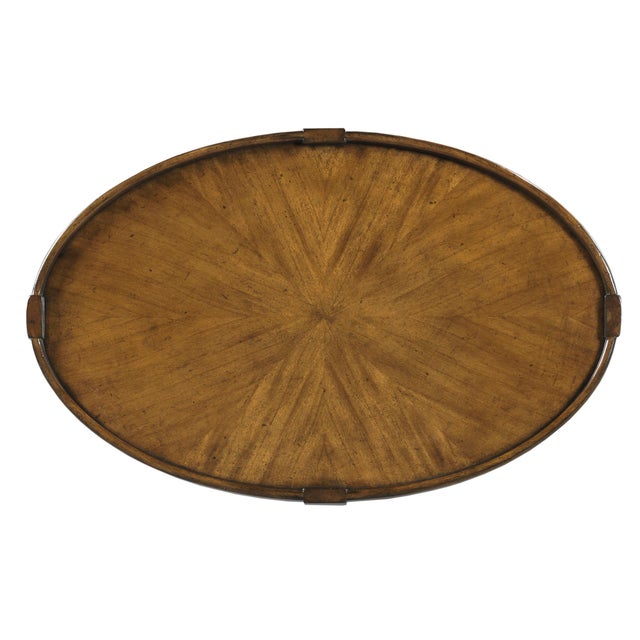 An oval top has a wrap around gallery that is elevated by graceful saber legs that are joined by a low shelf.