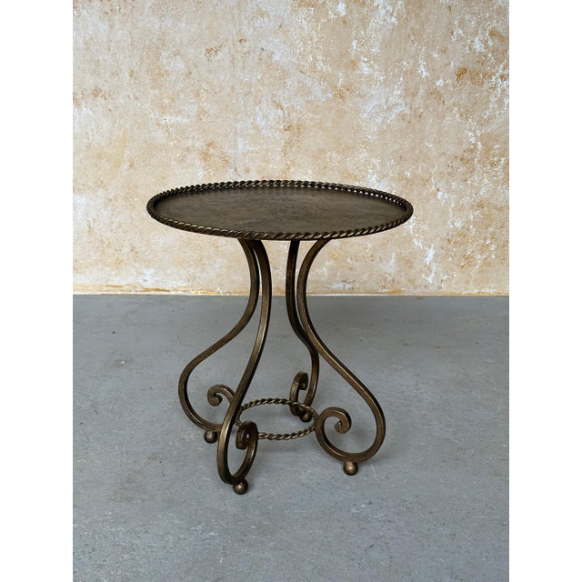 This distinctive vintage Spanish gilt iron drinks or side table, dating to the 1950s, features an intricately shaped hand-...