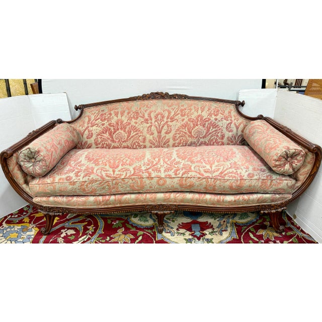 Presenting an exquisite antique carved mahogany sofa, upholstered in luxurious Fortuny fabric and finished with plush...