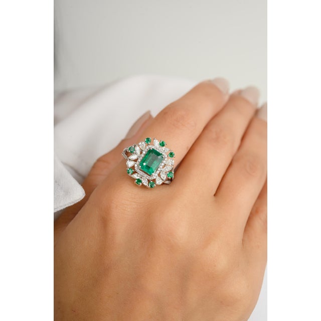 This stunning 18k white gold cocktail ring features a brilliant princess-cut emerald, complemented by sparkling diamonds....