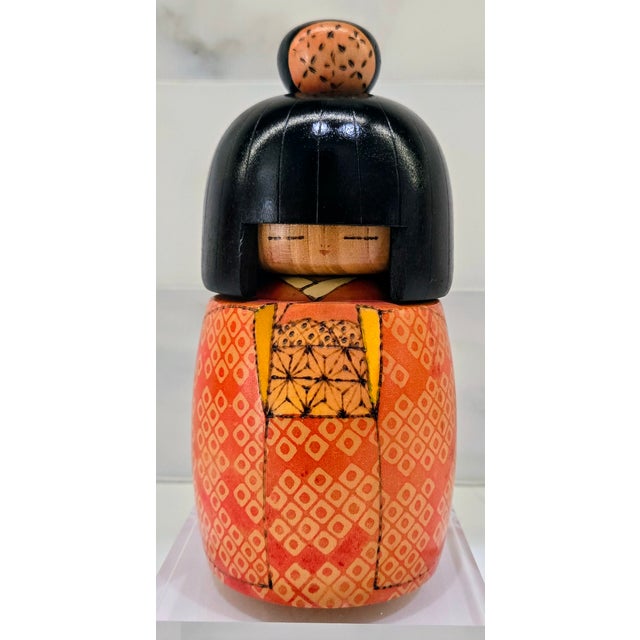 Charming vintage Japanese kokeshi doll featuring a serene, minimalist face framed by a glossy black bob and topknot,...