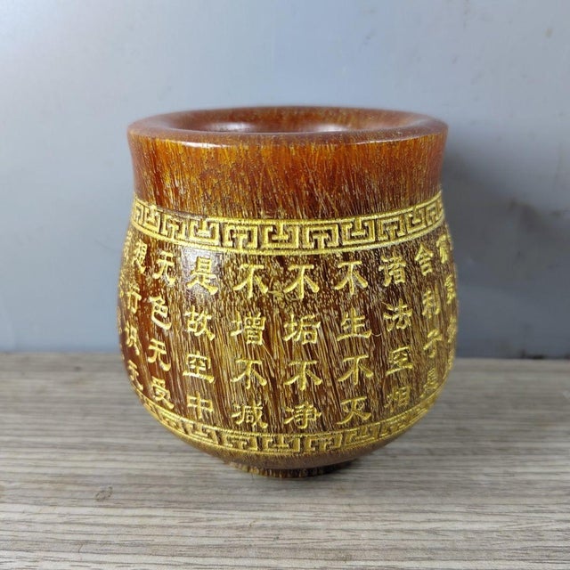 A striking Chinese carved horn cup (libation cup) featuring a rich, translucent amber-brown material with natural linear...