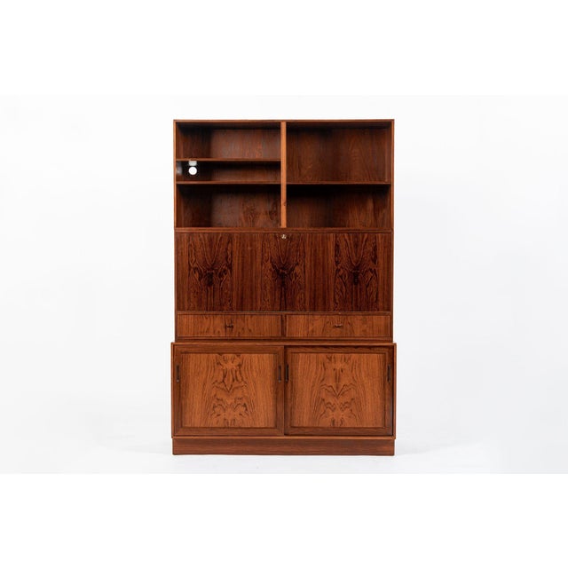 This vintage mid century Danish modern tall rosewood bookcase with secretary desk made in Denmark circa 1960 features a...