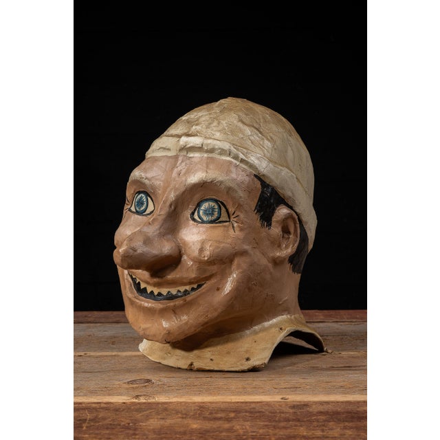 Large hand-painted papier-mâché carnival or funhouse character mask depicting a grinning male figure with dramatically...