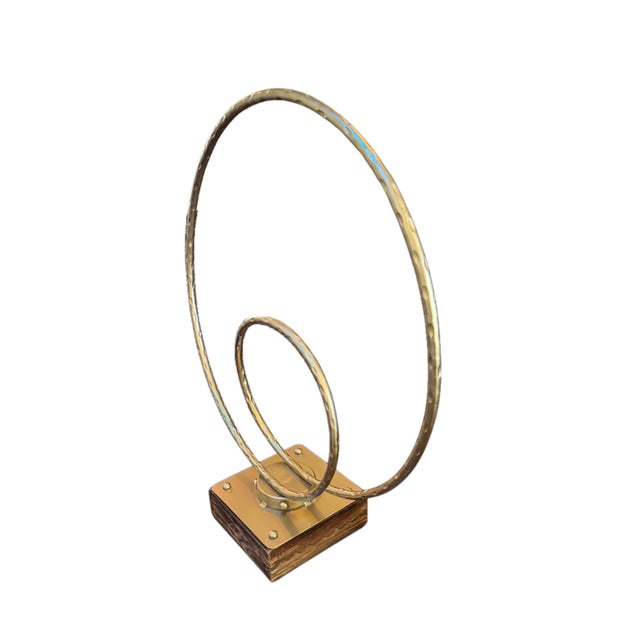 Striking modern sculptural object featuring two organically shaped hammered metal rings mounted on a warm stained wood...