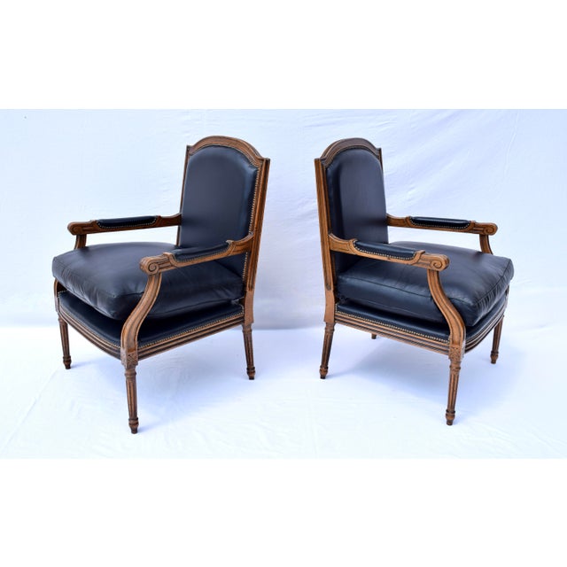 A pair of late 20th Century Louis XVI style plush leather Fauteuils with carved walnut frames & brass tack detailing....