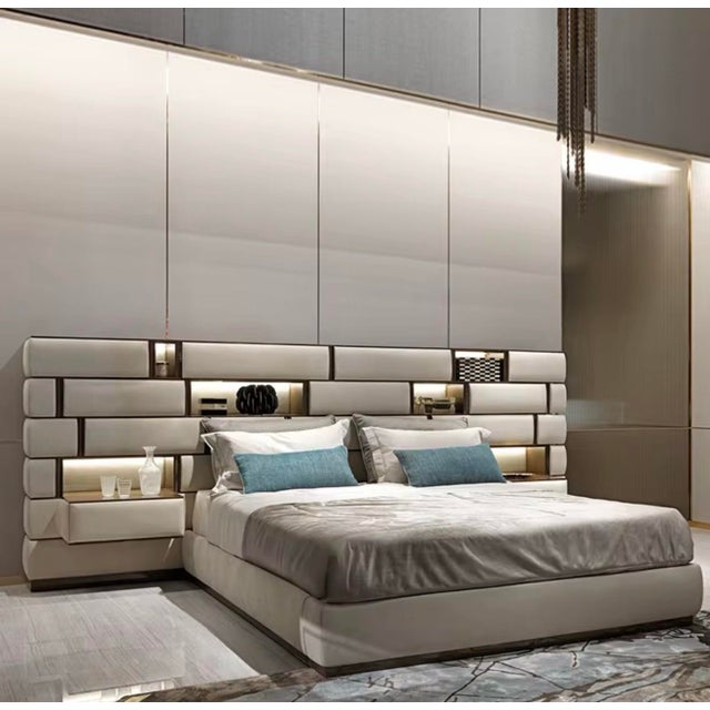 A modern Italian-style upholstered king bed designed with a dramatic extended headboard, integrated display shelving, and...