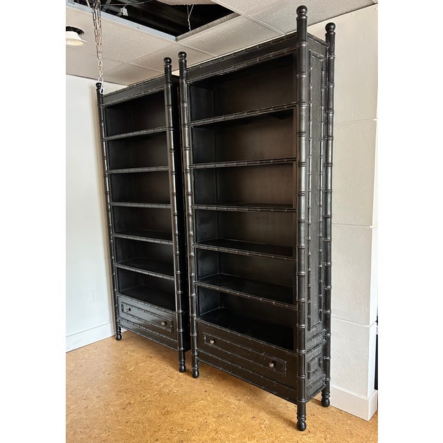 Stunning pair of vintage black faux bamboo etagere bookcases. Monumental Chinoiserie bookcase with one drawer at the base....