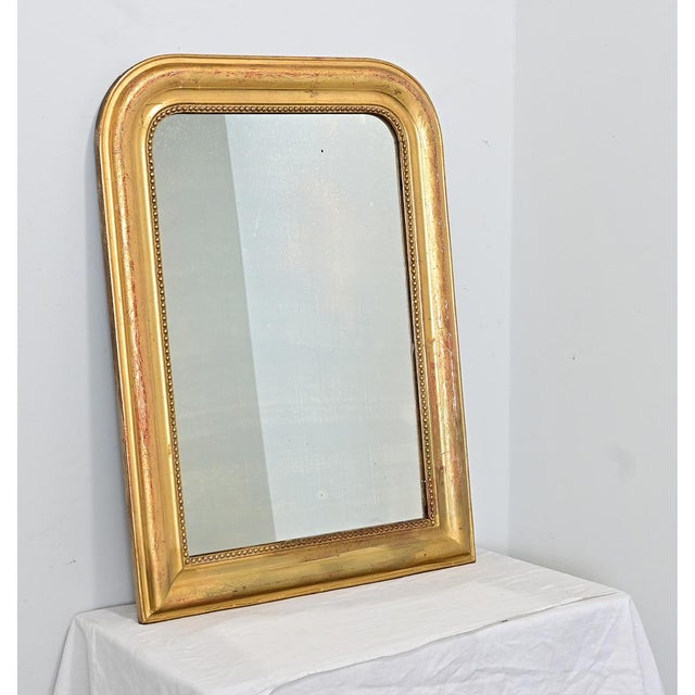A classic French gilt mirror from the 19th century, in that iconic Louis Philippe arched frame, enclosing the original...