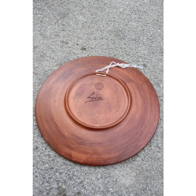 This round Paolo Loddo plate features artistic ceramic designs of figures and birds from Dorgali, Sardinia.