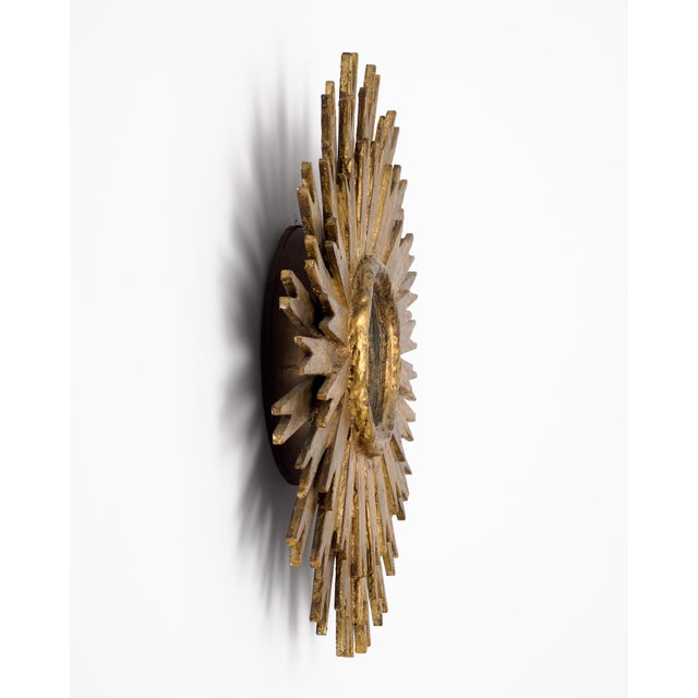 Elegant vintage Spanish sunburst mirror, circa 1980, crafted from carved wood and finished in hand-applied gold leaf....