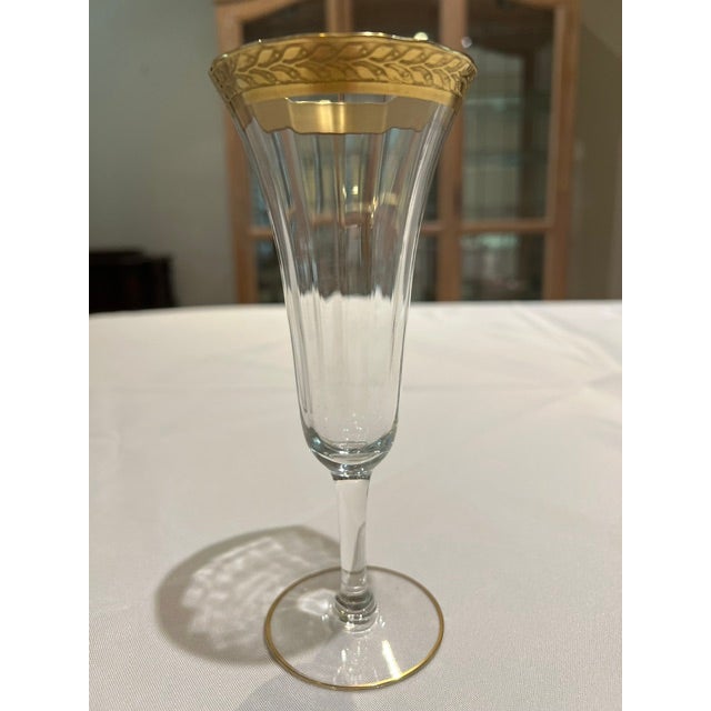 Four very pretty fluted champagne glasses with decorative gold band at top and gold rimmed feet.