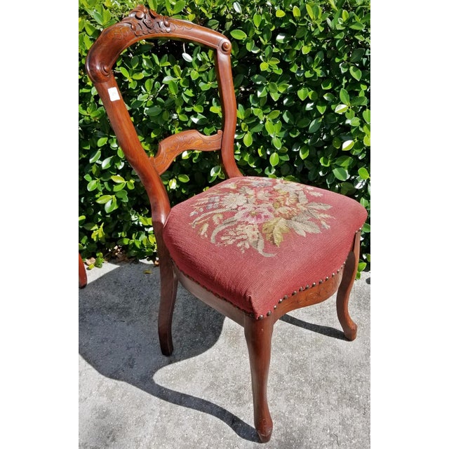 Sweet pair of carved mahogany 1880s American Victorian side chairs with handmade floral needlepoint seats perfect for a...