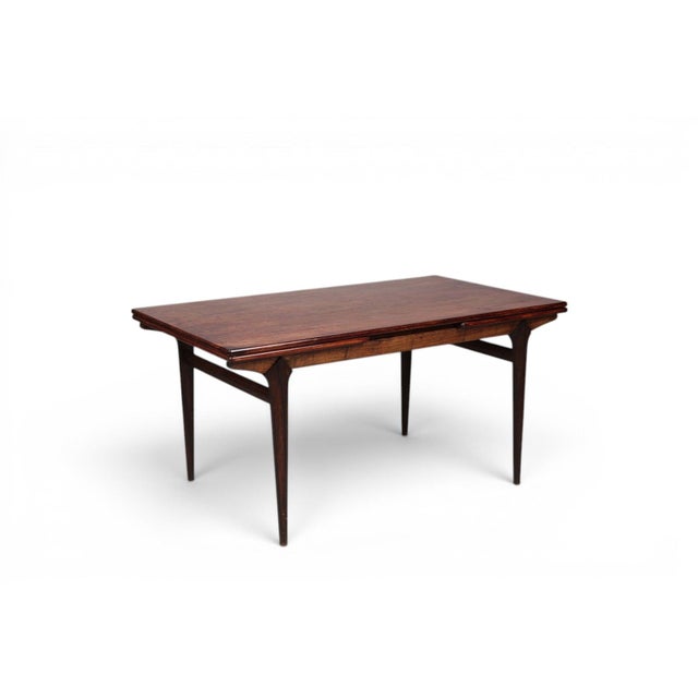 A breathtaking 1950s Danish draw leaf dining table by Johannes Andersen for Uldum Møbelfabrik in rich Brazilian rosewood....