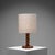 Distinguished by its finely carved hardwood base, this table lamp exemplifies the sculptural approach to decorative arts...