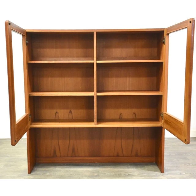 A mid century modern teak display case cabinet or bookcase with glass doors. Made in Denmark. 47.25” wide. 13” deep. 49”...