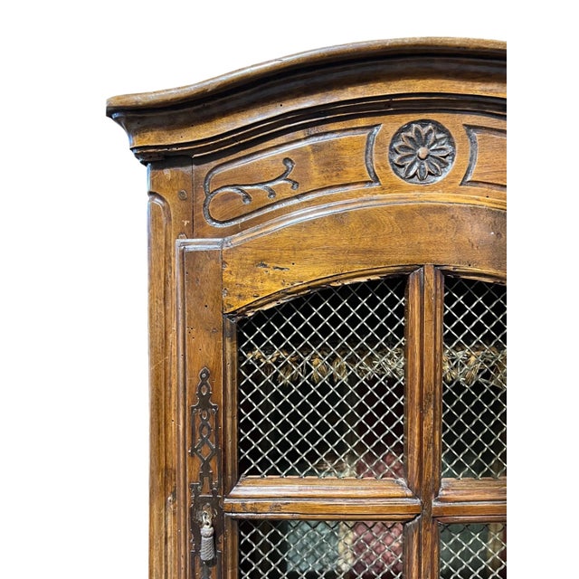 An 18th century French hanging cabinet made of walnut. The front cabinet door has the original brass grill and hardware....