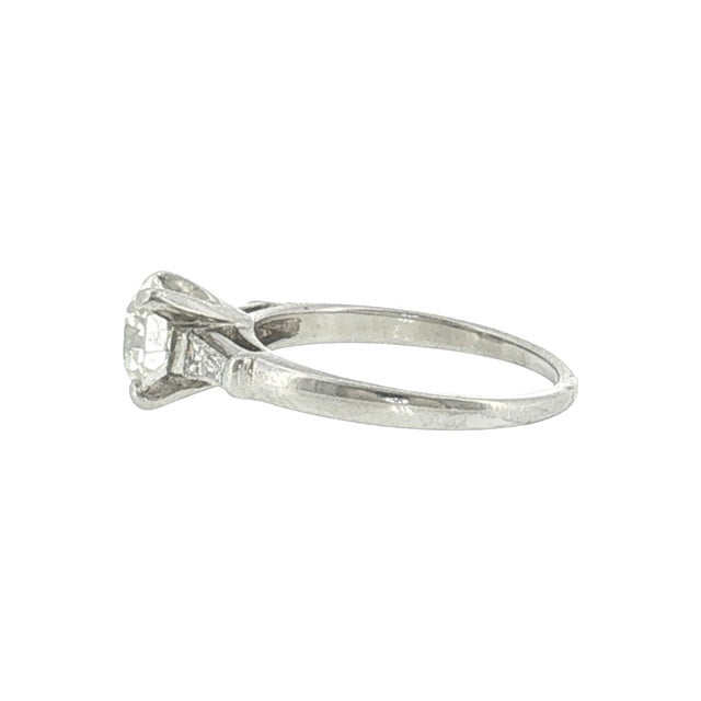 A mid-century engagement ring featuring a 0.94-carat Old European cut diamond. The primary stone is white, with a clarity...