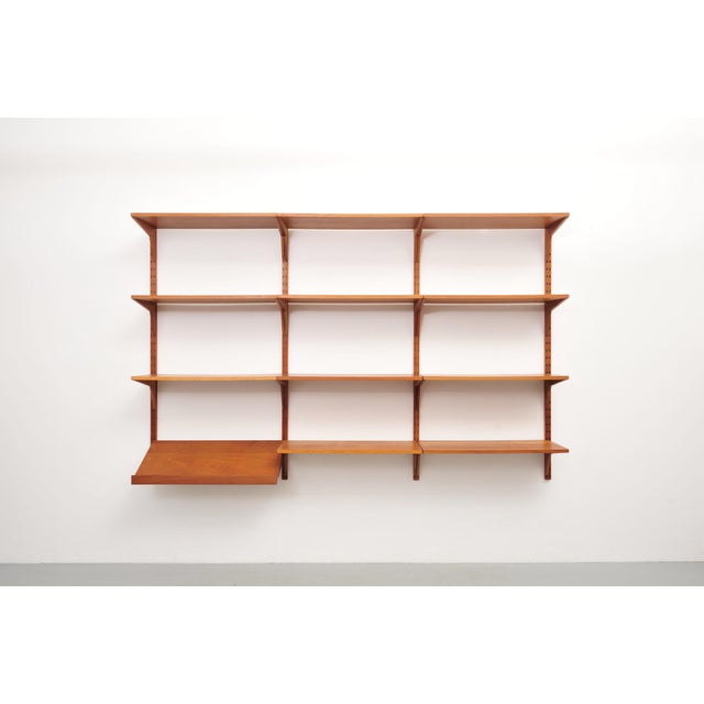 Shelving system from the 1950s, designed by Poul Cadovius for CADO. Made of teak, with eleven shelves, a newspaper rack,...