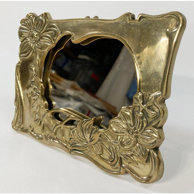 Vintage brass vanity table mirror. Brass frame features detailed floral pattern. Mirror could be removed for use as a...