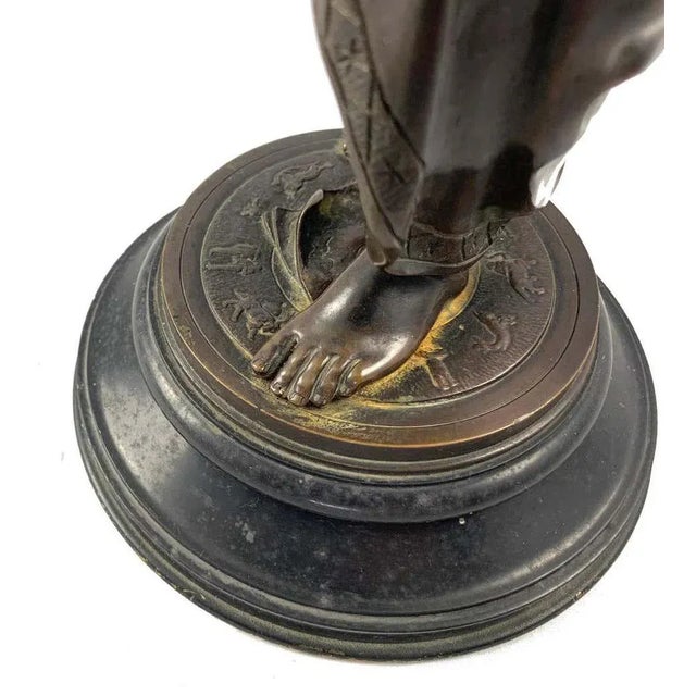 A french cast bronze figure of a classical maiden, circa 1900. Dark brown patination. Shown standing wearing draped robes....