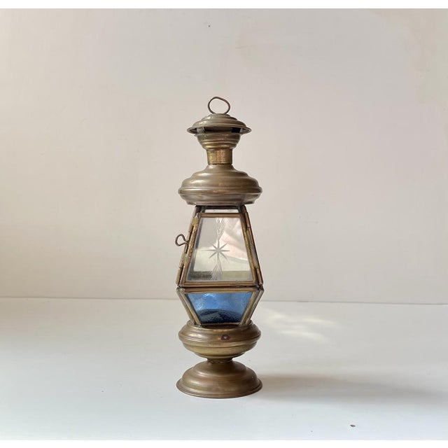 A small scaled lantern executed in patinated brass and featuring panels of colored and etched glass. It has a tea light as...