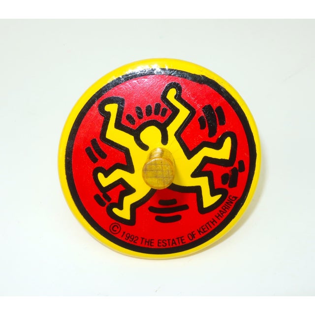 Keith Haring (1958-1990) yellow and red lacquered wood spinning top featuring his iconic image entitled 'Dancing Man'....