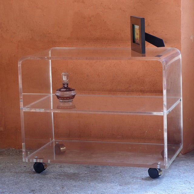 Vintage cart made of clear acrylic glass with gold-plated wheels for easy movement. Ideal as a stand for a stereo or TV,...