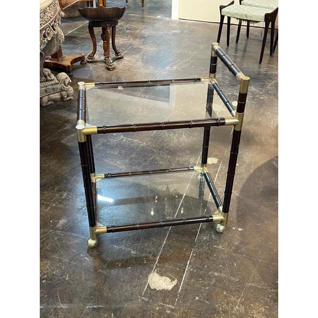 Very nice Italian mid century modern brass and bamboo form bar car. The piece has 2 glass shelves and is on casters....