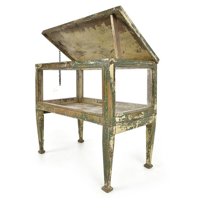 This antique wooden display case, mounted on four tapered legs, seduces with its multicolored patina and slender...