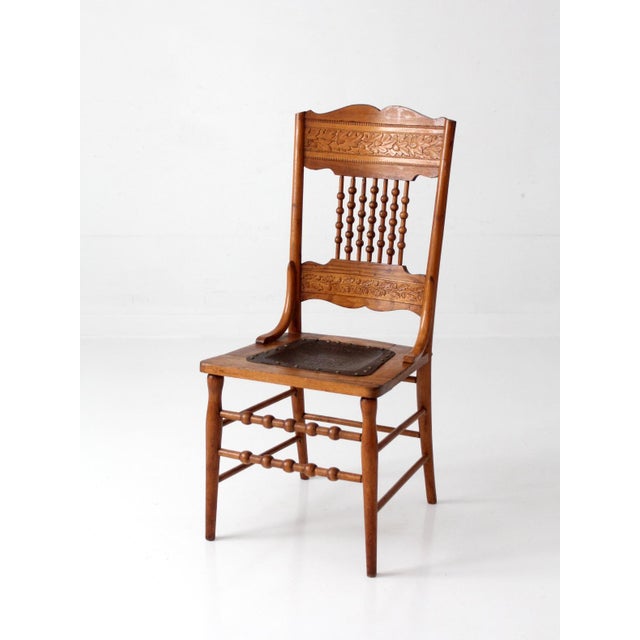 A striking late 19th-century Victorian Eastlake chair featuring beautifully carved oak leaf details, turned spindle...