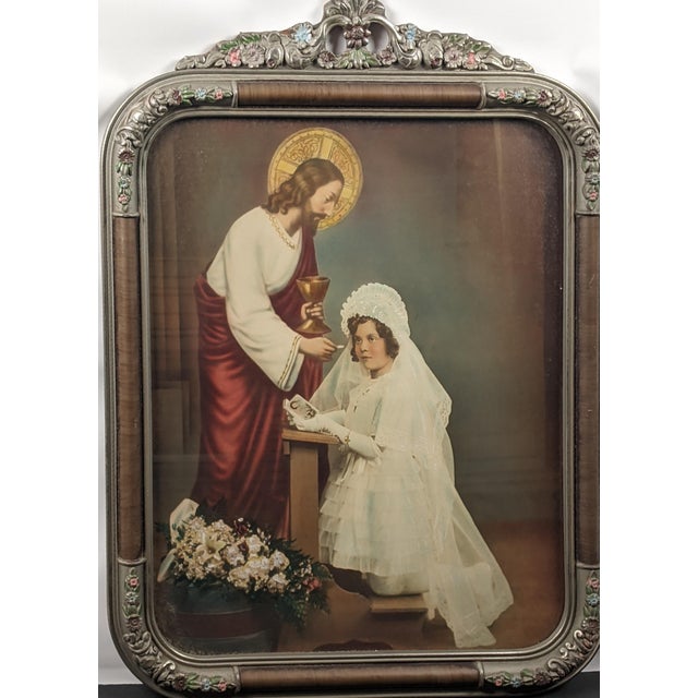 Striking 1938 First Communion devotional portrait presented in an elaborate silvered and polychrome floral frame. The...