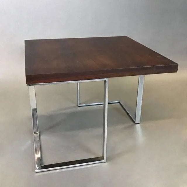 Striking, modernist coffee or side table features a rosewood top with architectural chrome bases is very much in the style...
