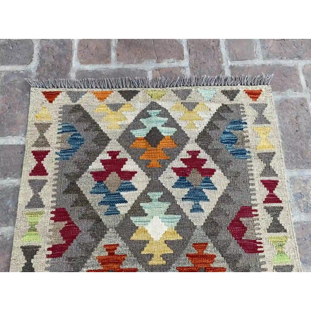 Add a splash of vibrant color to your living space with this colorful handwoven wool kilim rug. Featuring a stunning...