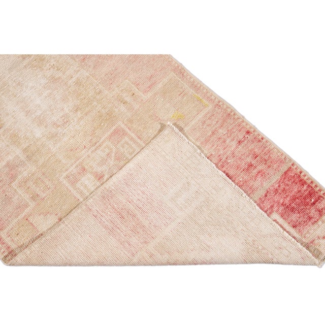 Beautiful vintage Turkish hand-knotted wool rug with a beige field. This rug has accents of ivory and pink in a gorgeous...