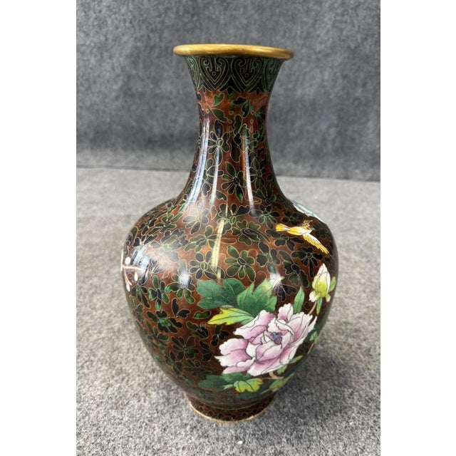 This brown cloisonné vase is adorned with beautifully detailed birds and colorful flowers against a dark enamel...