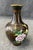 This brown cloisonné vase is adorned with beautifully detailed birds and colorful flowers against a dark enamel...