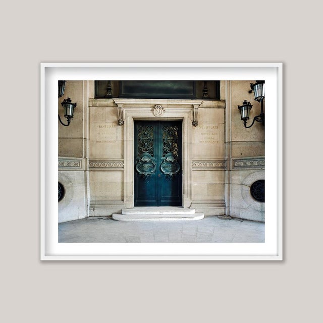 An architectural photograph of the Louvre Museum in Paris, France. Above the entrance to the galleries, the letter N for...
