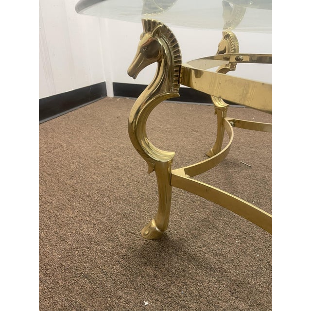 Nice brass and glass coffee table with six seahorse legs. The glass top has a beveled edge.