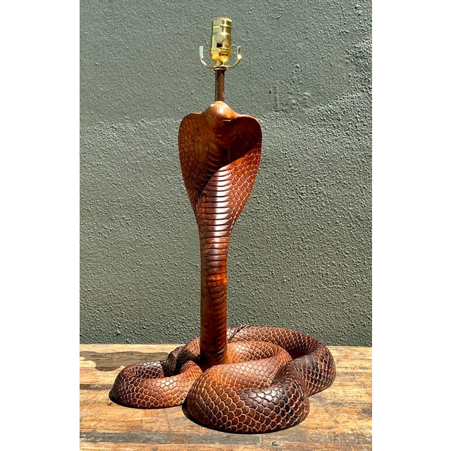 This striking vintage table lamp is a masterpiece of artisan woodcarving, featuring a dramatic cobra coiled in a powerful,...