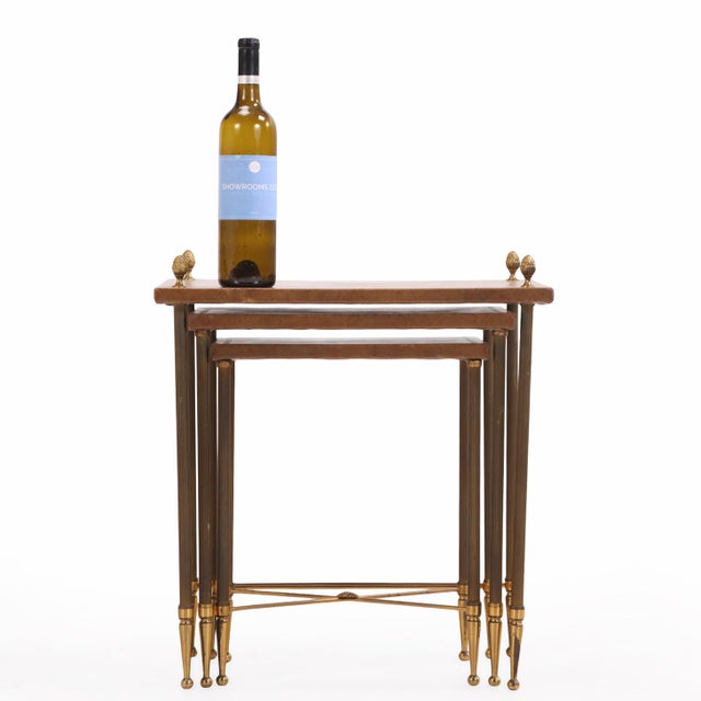 The graduated tables feature brass frames with inset embossed leather tops, the largest surmounted by decorative brass...