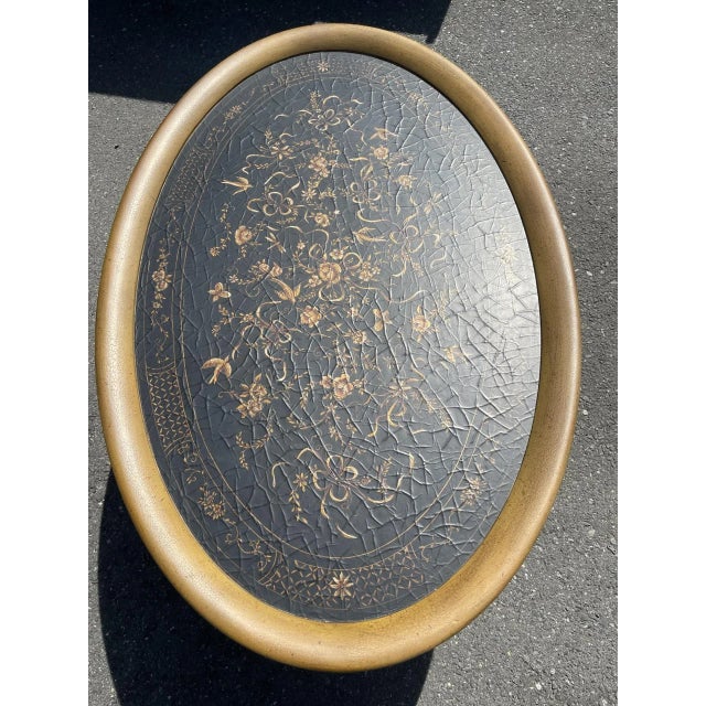 A Pennsylvania House Chinoiserie gold and black oval coffee table. Features include a bamboo-like frame, a pull-out drink...