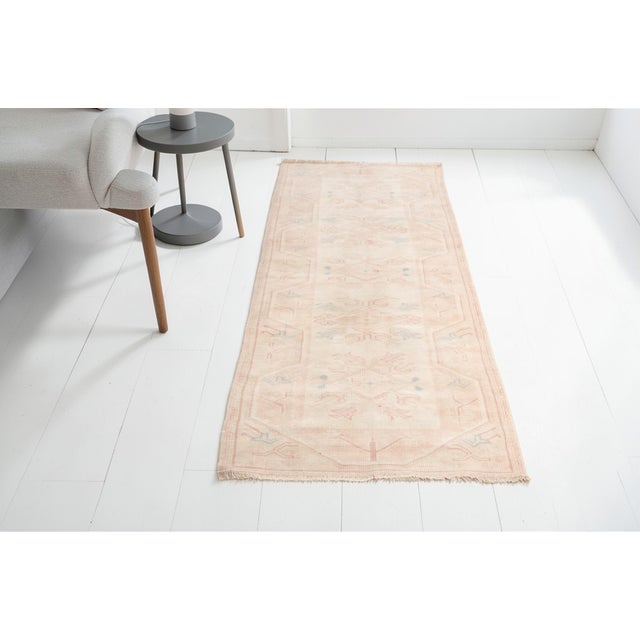 This is a vintage Turkish Oushak rug from the Mid 20th Century. The piece was hand-knotted.