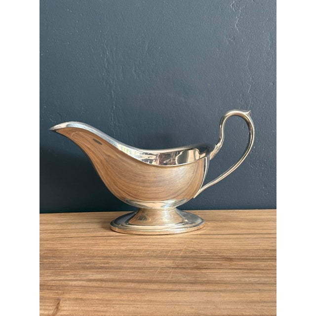 A classic silverplated gravy or sauce boat with a deep oval body, wide pouring lip, high looped handle with thumb-rest,...